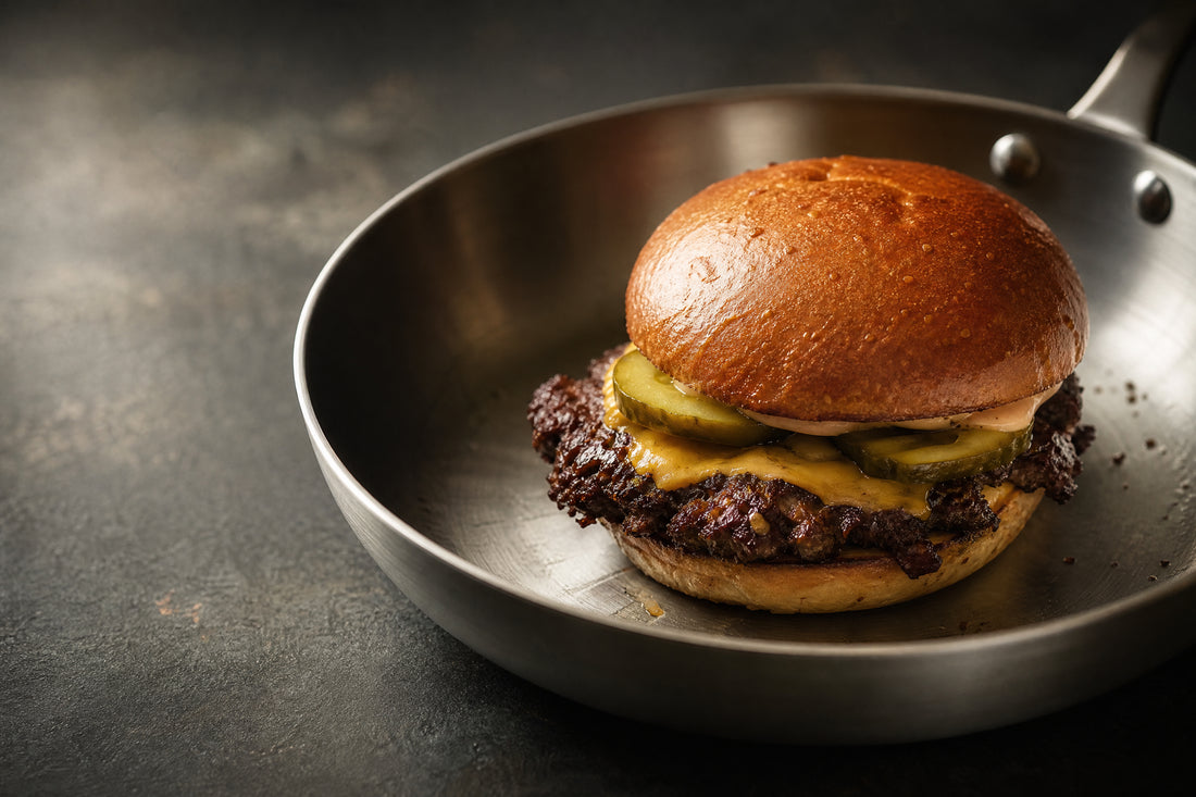 Smash burger maison à la croûte dorée dans une poêle en inox