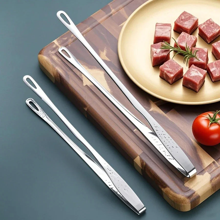 Pinces de chef en inox posées sur une planche, près de dés de viande