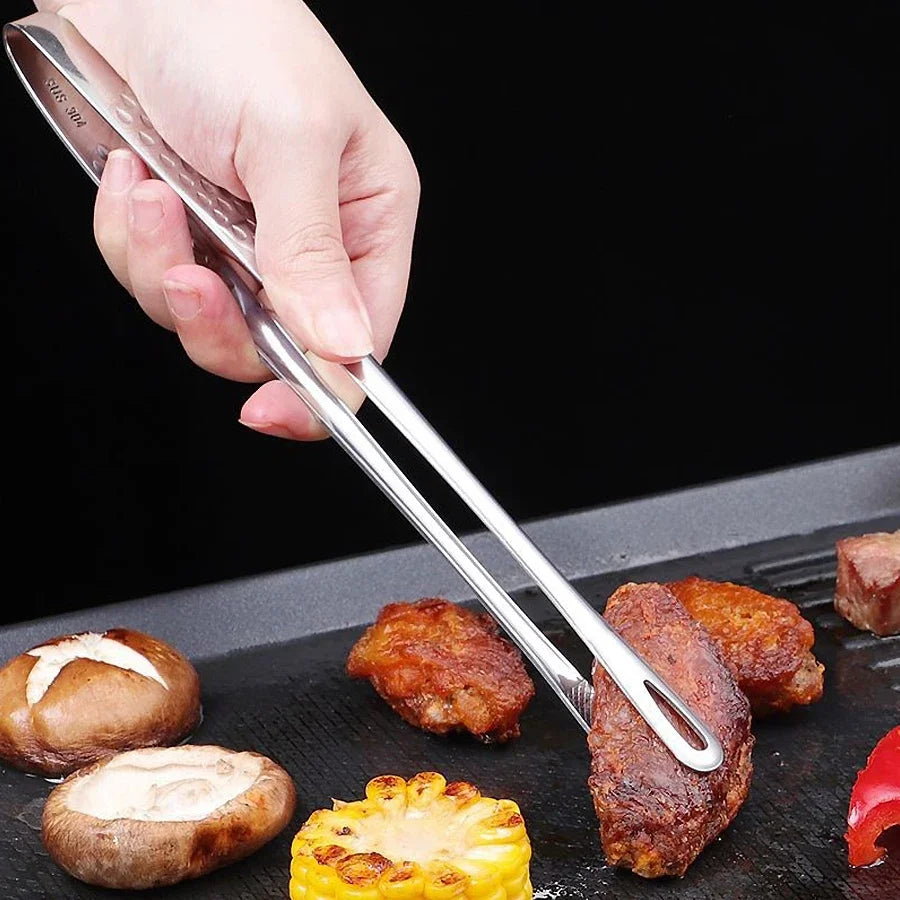 Pince de chef en inox retournant des aliments sur une plaque