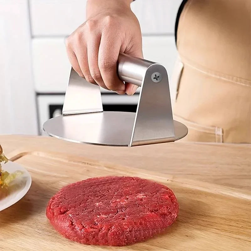 Presse à smash burger en inox tenue en main au-dessus d'un steak haché