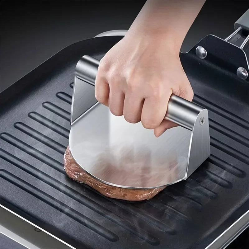 Presse à burger en inox écrasant un steak sur une plaque chaude
