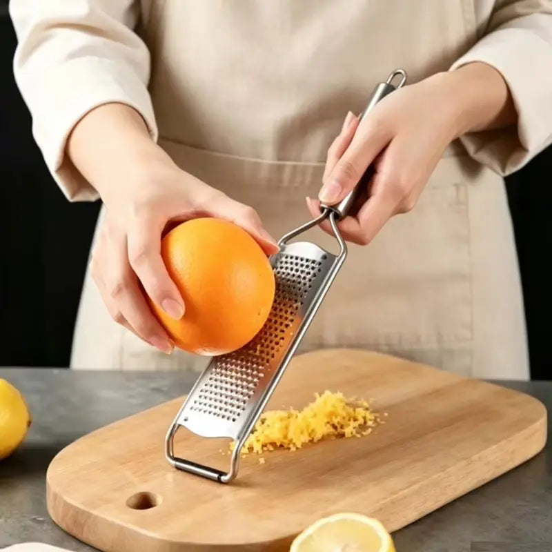 Zeste d'orange râpé sur une planche avec la râpe zesteur en inox